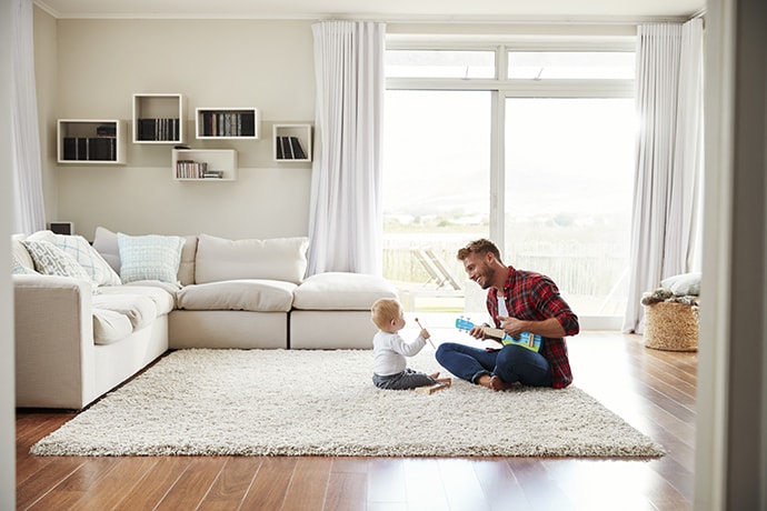Father playing ukulele with young son in their sitting room